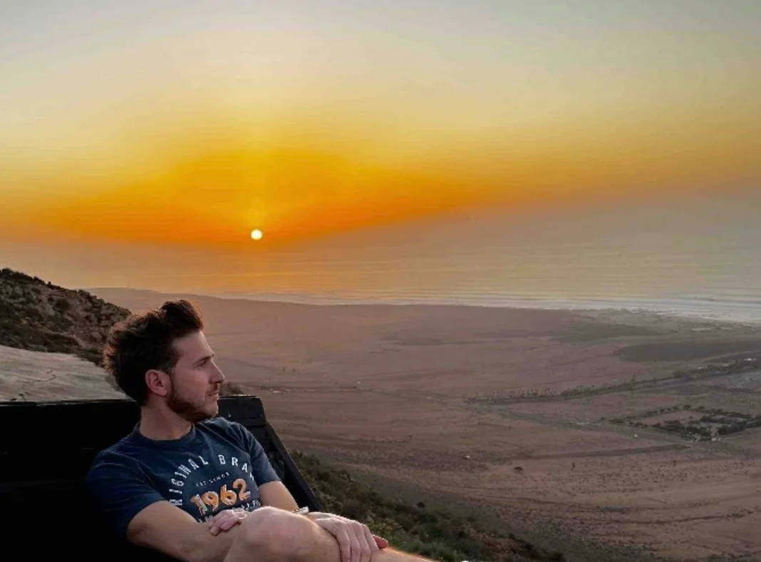 Voyageur face au coucher de soleil sur la côte atlantique du Maroc
