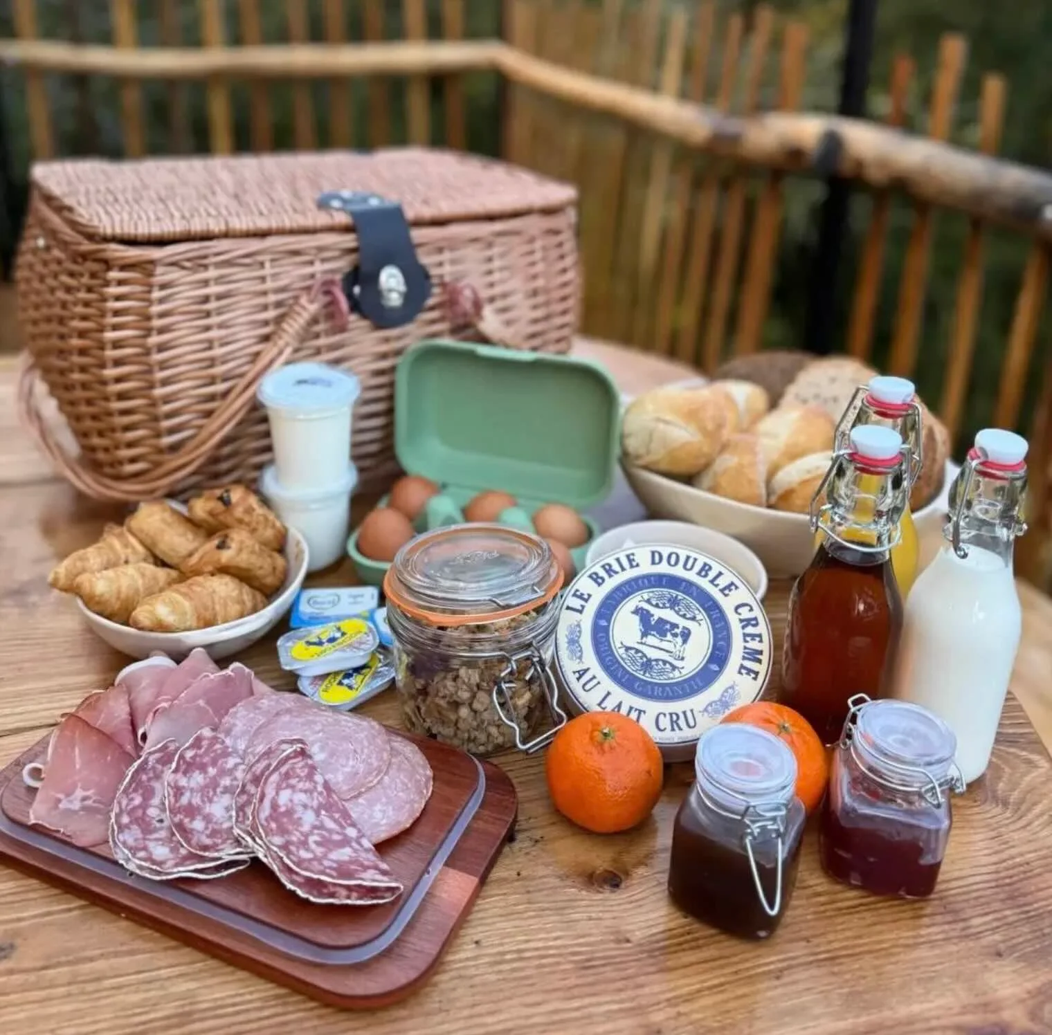 Panier de petit-déjeuner garni de produits locaux sur une table en bois