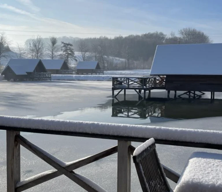 Lodges AquaLodge sur pilotis au bord d’un étang enneigé près de Maredsous