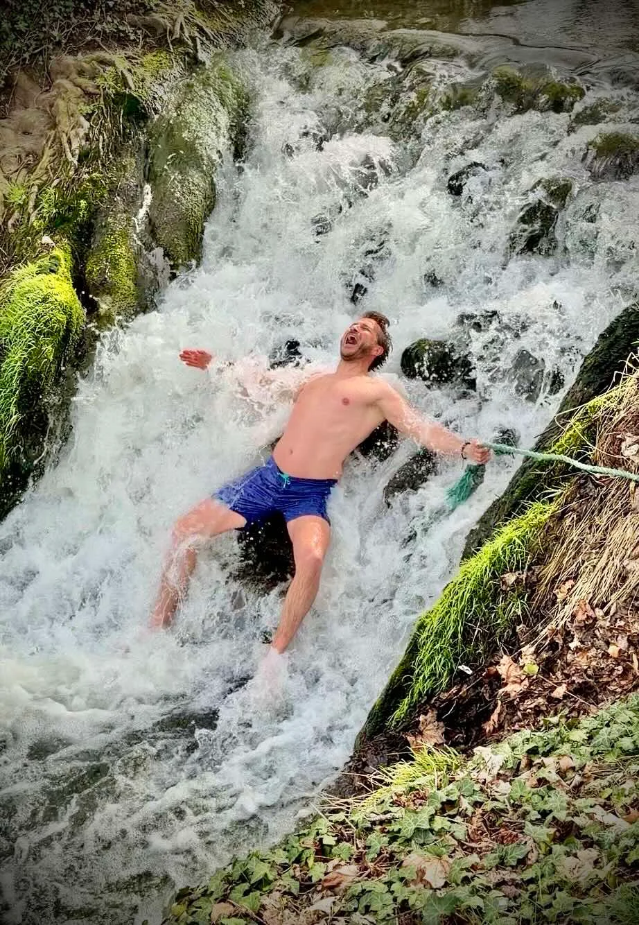 Voyageur expérimentant l’eau froide d’une petite cascade près de Room8