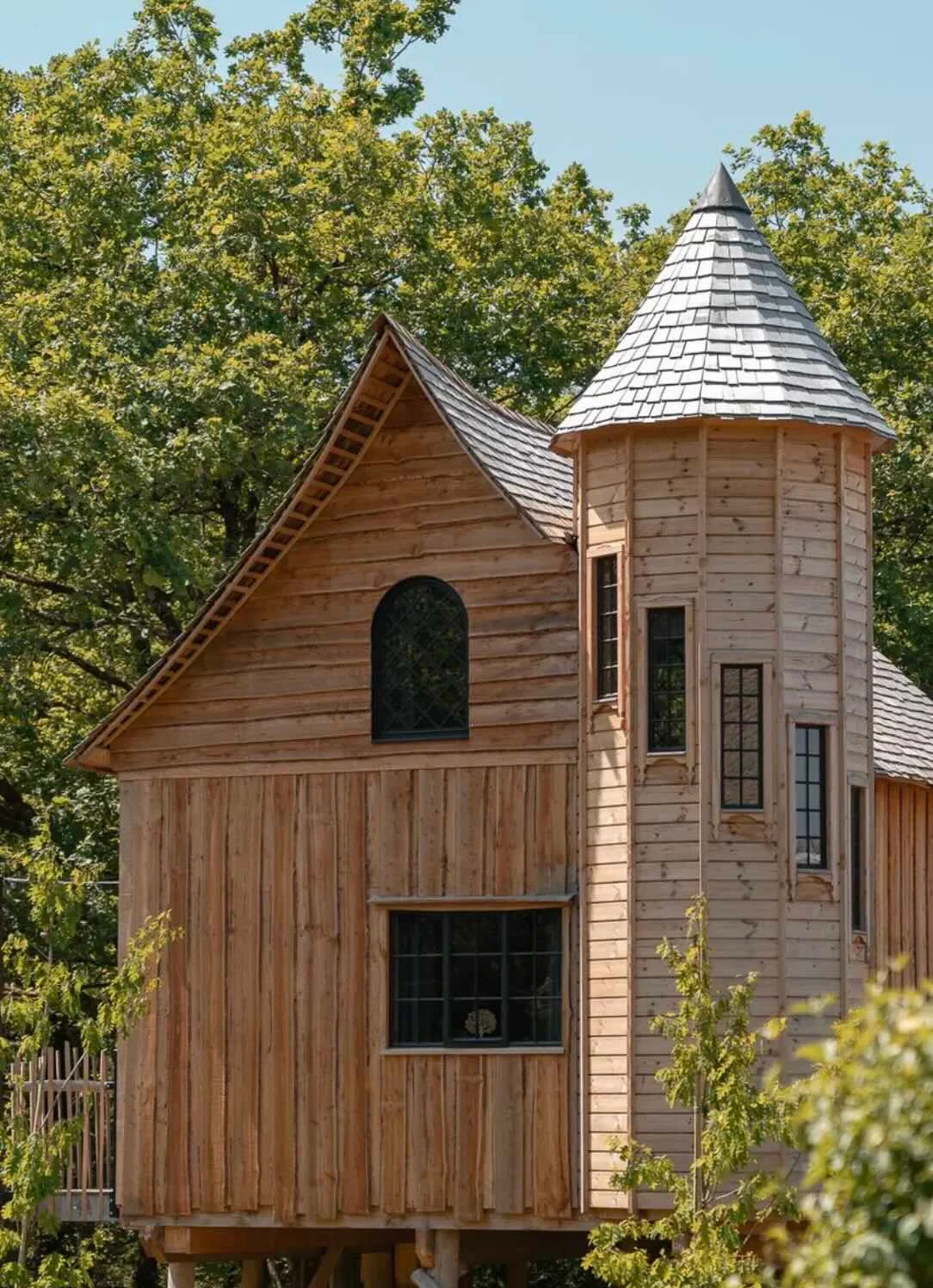 Façade en bois et petite tour d’un Treelodge entouré d’arbres